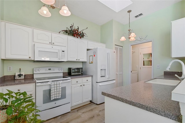 kitchen featuring white appliances, sink, pendant lighting, a notable chandelier, and white cabinetry