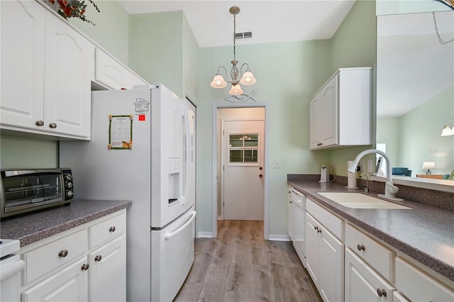 kitchen with light wood-type flooring, white appliances, sink, an inviting chandelier, and white cabinetry