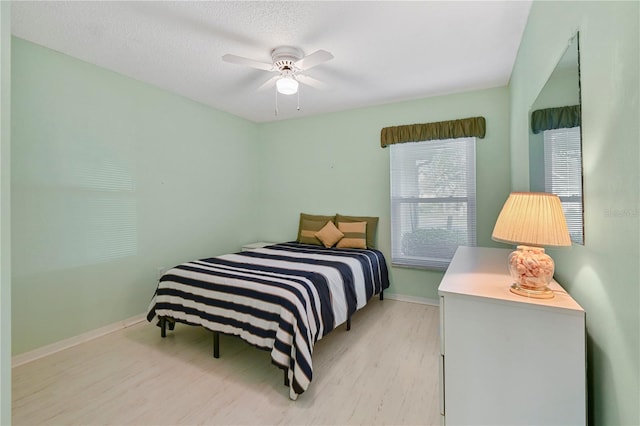 bedroom with ceiling fan, a textured ceiling, and light hardwood / wood-style flooring