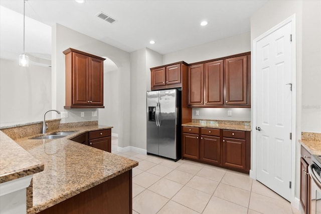 kitchen with sink, light stone counters, appliances with stainless steel finishes, light tile patterned floors, and hanging light fixtures