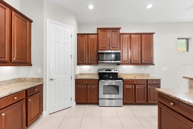 kitchen with light stone countertops, light tile patterned floors, and appliances with stainless steel finishes