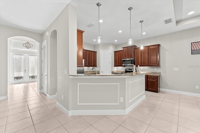 kitchen featuring light stone counters, appliances with stainless steel finishes, light tile patterned floors, hanging light fixtures, and a chandelier