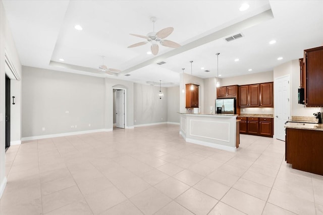 kitchen featuring stainless steel refrigerator with ice dispenser, ceiling fan, a raised ceiling, light stone countertops, and pendant lighting