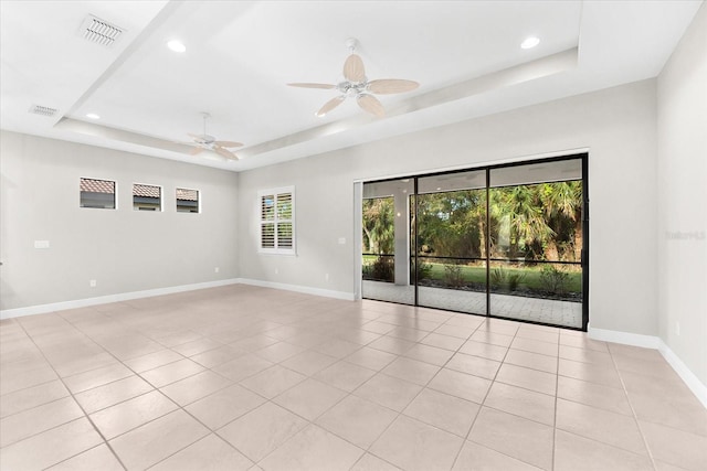 tiled spare room featuring ceiling fan and a raised ceiling