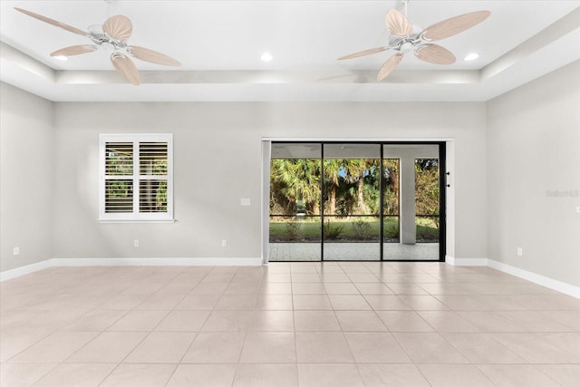 tiled empty room with ceiling fan and a raised ceiling