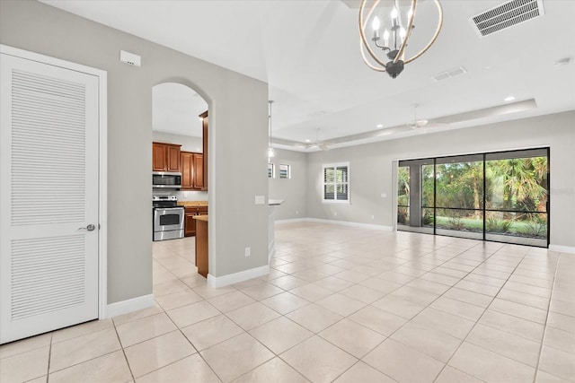 unfurnished living room featuring a tray ceiling, light tile patterned flooring, and ceiling fan with notable chandelier