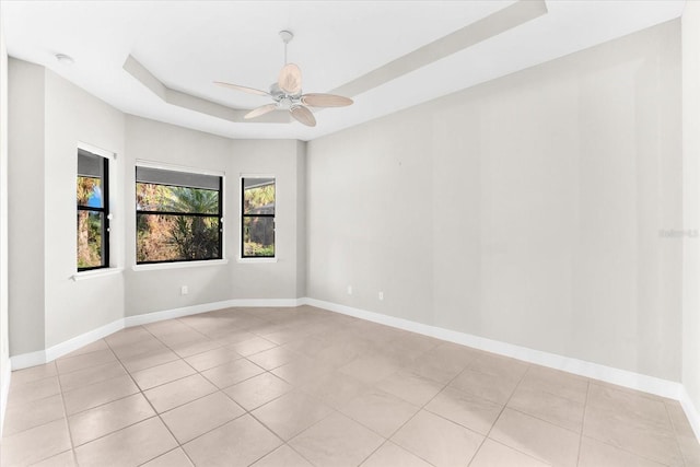 spare room featuring light tile patterned flooring, a tray ceiling, and ceiling fan