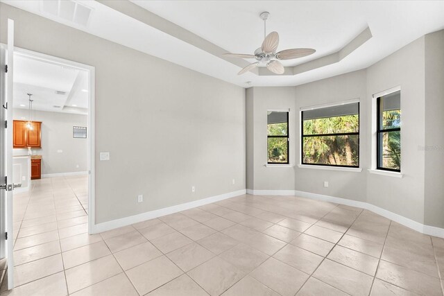 unfurnished room featuring light tile patterned flooring, a raised ceiling, and ceiling fan