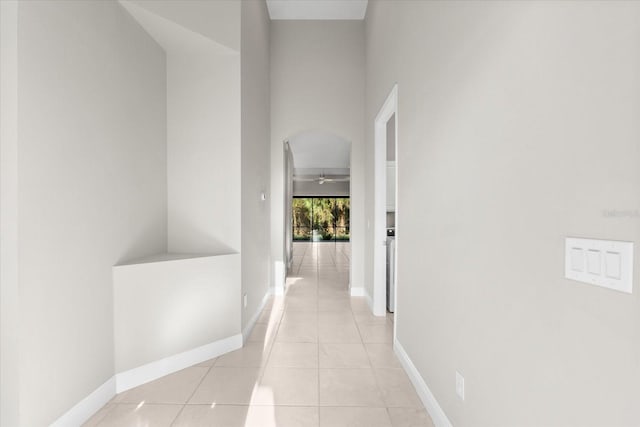 hall featuring light tile patterned flooring and a towering ceiling