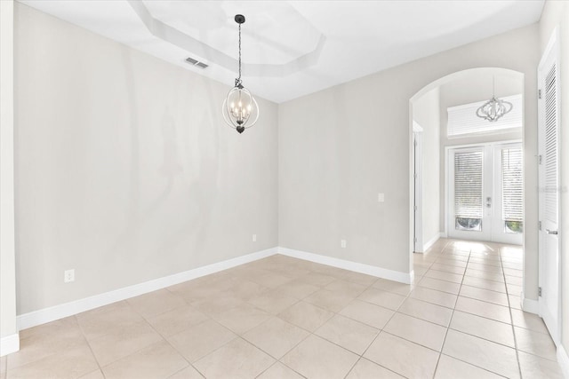 unfurnished room with light tile patterned floors, a chandelier, a raised ceiling, and french doors