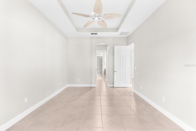 spare room featuring light tile patterned flooring, ceiling fan, and a tray ceiling