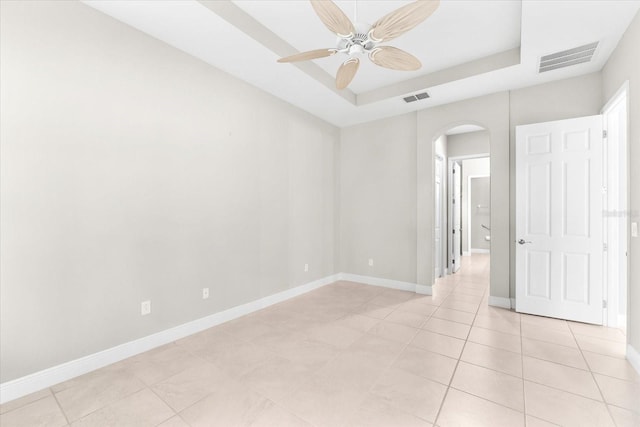 tiled spare room with ceiling fan and a raised ceiling