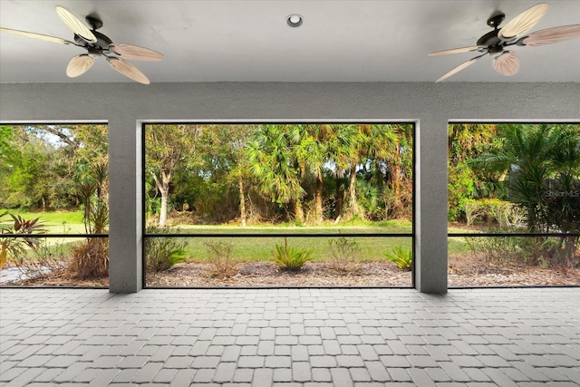 unfurnished sunroom featuring ceiling fan