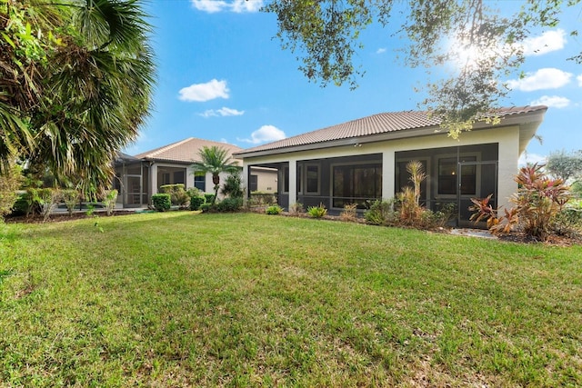 rear view of house featuring a sunroom and a lawn