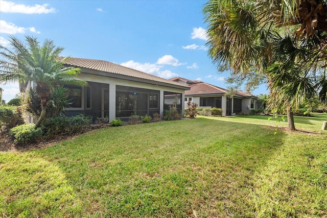 rear view of property featuring a sunroom and a yard