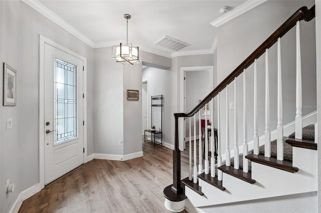 foyer with an inviting chandelier, light hardwood / wood-style floors, and ornamental molding