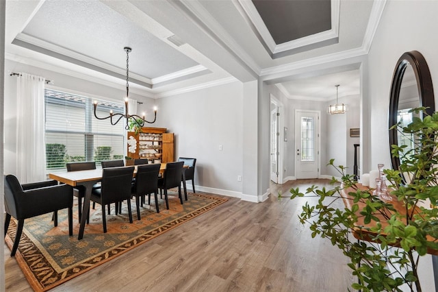 dining space with crown molding, plenty of natural light, hardwood / wood-style floors, and an inviting chandelier