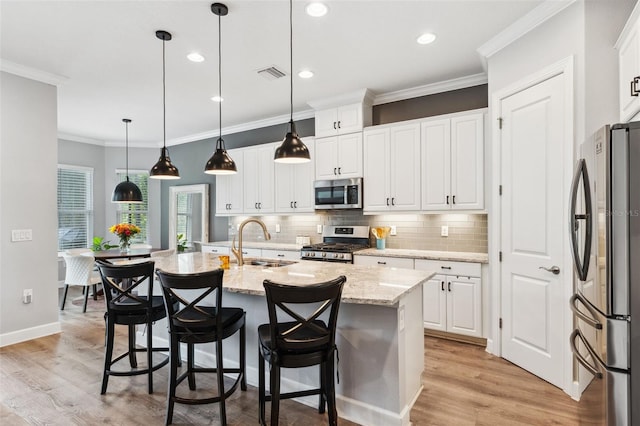 kitchen featuring white cabinets, sink, stainless steel appliances, and an island with sink