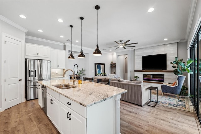 kitchen with an island with sink, white cabinetry, ceiling fan, and sink