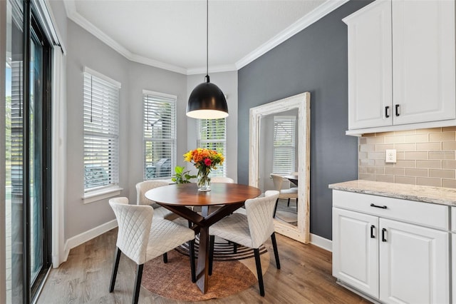 dining space with crown molding, plenty of natural light, and light wood-type flooring