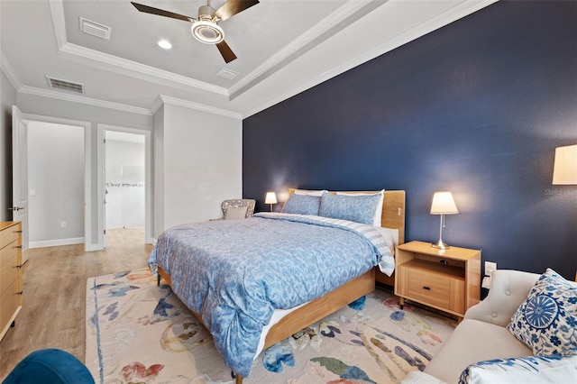 bedroom with a tray ceiling, ceiling fan, light hardwood / wood-style floors, and ornamental molding