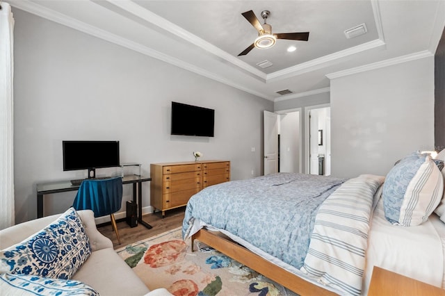 bedroom with ceiling fan, wood-type flooring, ornamental molding, and a tray ceiling