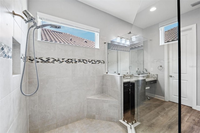 bathroom featuring hardwood / wood-style flooring, vanity, and tiled shower