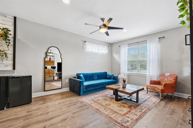 living room featuring a textured ceiling, light hardwood / wood-style flooring, and ceiling fan