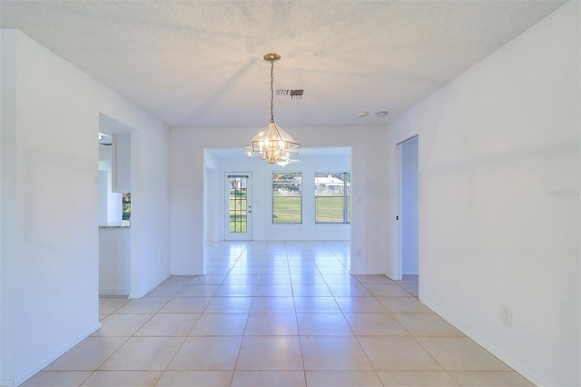 unfurnished dining area with a textured ceiling, light tile patterned floors, and a chandelier