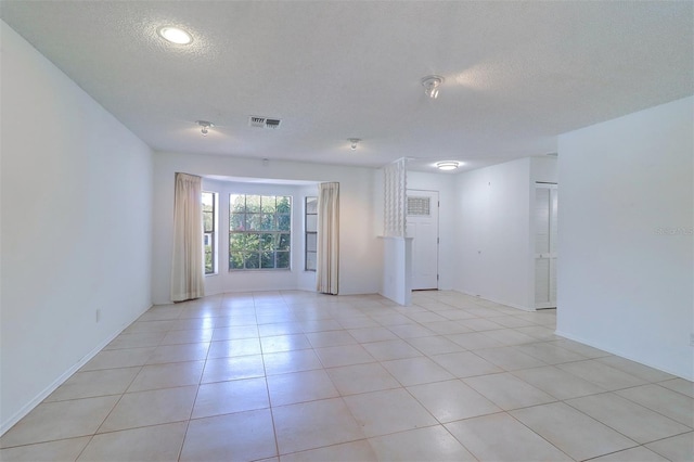 unfurnished room featuring a textured ceiling and light tile patterned floors