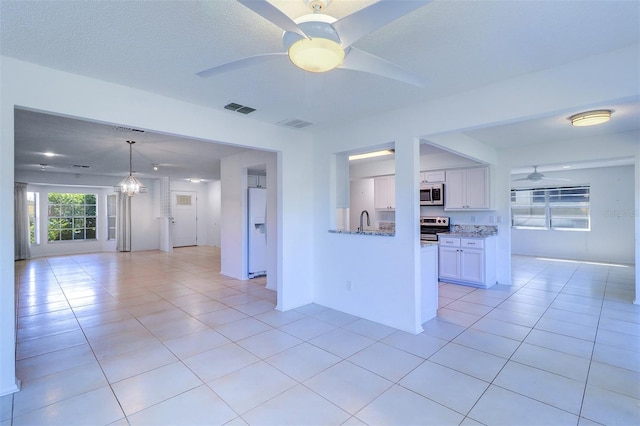 kitchen featuring white cabinetry, sink, light stone counters, appliances with stainless steel finishes, and light tile patterned floors