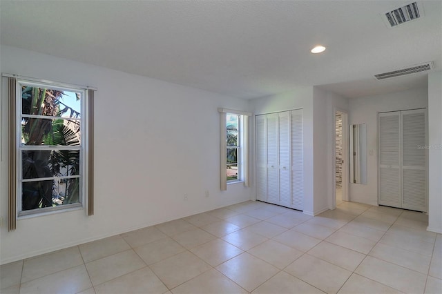 interior space with two closets and light tile patterned floors