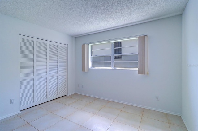 unfurnished bedroom with light tile patterned floors, a textured ceiling, and a closet