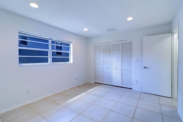 unfurnished bedroom with a closet, a textured ceiling, and light tile patterned flooring