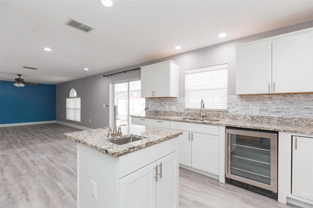 kitchen with white cabinetry, sink, and beverage cooler