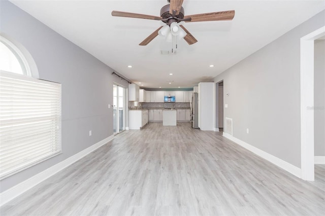 unfurnished living room featuring light hardwood / wood-style flooring and ceiling fan