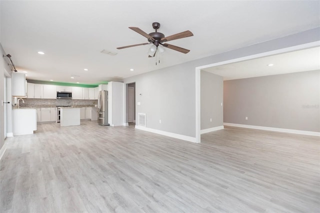 unfurnished living room featuring ceiling fan, sink, and light hardwood / wood-style floors