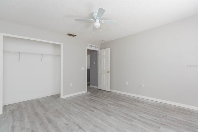 unfurnished bedroom featuring a textured ceiling, a closet, light hardwood / wood-style flooring, and ceiling fan