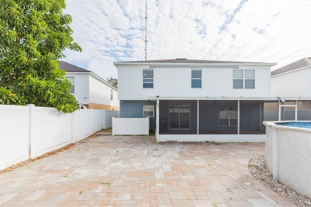 rear view of property featuring a fenced in pool, a patio area, and a sunroom