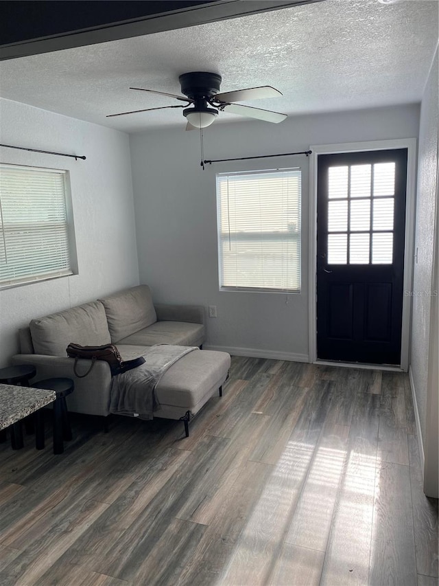 living room with ceiling fan, dark hardwood / wood-style floors, and a textured ceiling