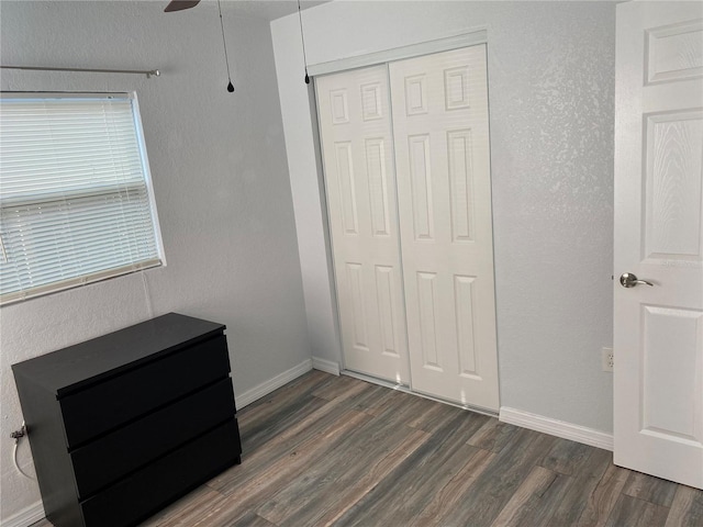 unfurnished bedroom with dark hardwood / wood-style flooring, a closet, and ceiling fan