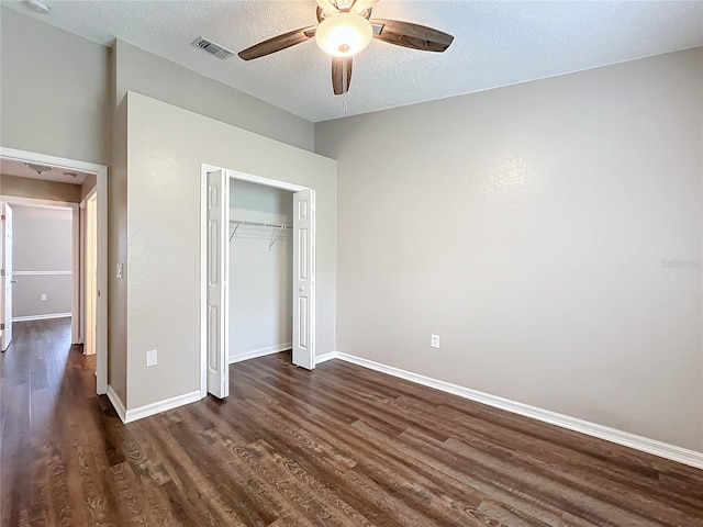 unfurnished bedroom with dark wood-type flooring, ceiling fan, a textured ceiling, and a closet