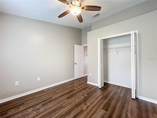 unfurnished bedroom featuring ceiling fan, a textured ceiling, a closet, and dark hardwood / wood-style flooring