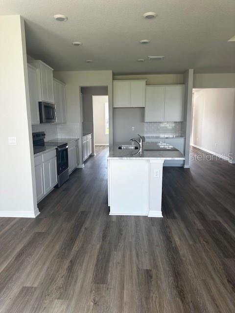 16021 7th Ave E, Bradenton, FL 34212 - kitchen with stainless steel microwave, electric range, baseboards, a sink, and dark wood-style floors
