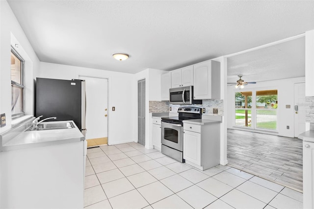 kitchen with decorative backsplash, sink, appliances with stainless steel finishes, a textured ceiling, and white cabinets