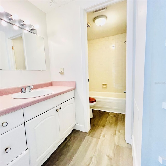 full bathroom featuring hardwood / wood-style flooring, toilet, vanity, and tiled shower / bath