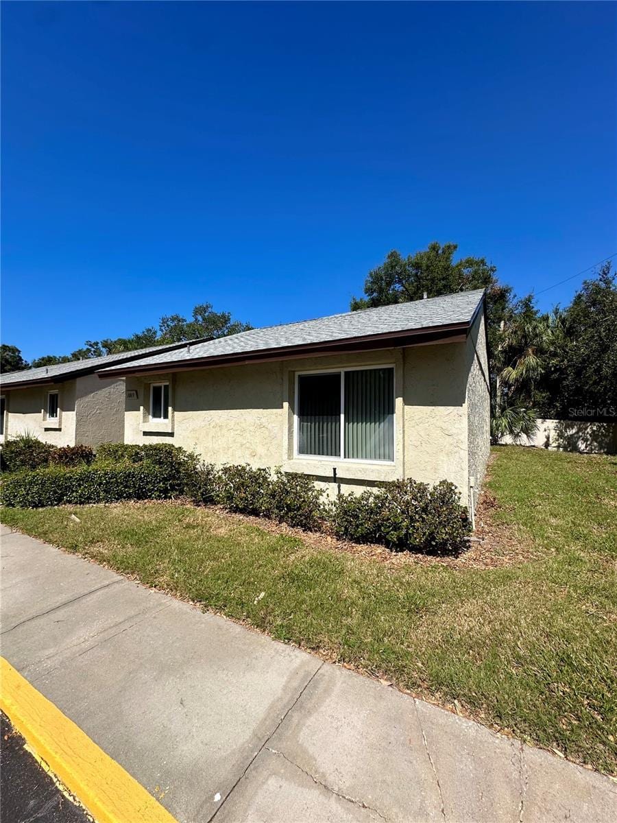 4215 E Bay Dr Unit 1013B, Clearwater, FL 33764 - view of side of home with stucco siding and a yard