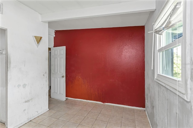 tiled empty room with vaulted ceiling with beams