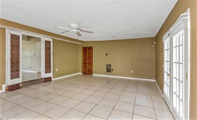 unfurnished room featuring ceiling fan, wooden walls, and light tile patterned floors