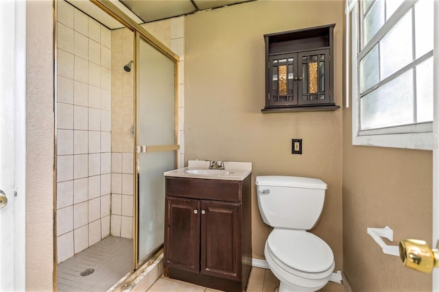 bathroom with tile patterned flooring, vanity, a shower with shower door, and toilet